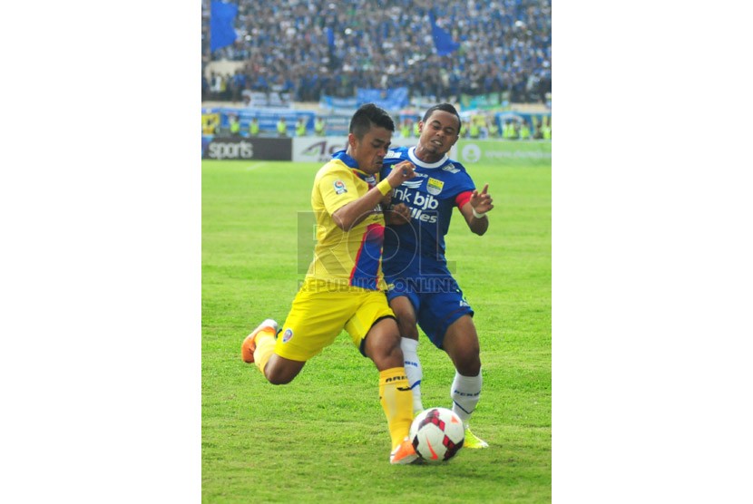 Pemain Arema Malang Benny Wahyudi (kiri) berebut bola dengan pemin Persib Bandung Atep (kanan) pada laga lanjutan Indonesia Super League di Stadion Si Jalak Harupat, Kabupaten Bandung, Ahad (13/4). (foto: Septianjar Muharam)