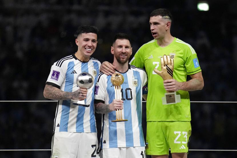  Pemain Argentina Enzo Fernandez, Lionel Messi dan kiper Emiliano Martinez, dari kiri ke kanan, berpose dengan penghargaan individu mereka pada akhir pertandingan sepak bola final Piala Dunia antara Argentina dan Prancis di Stadion Lusail di Lusail, Qatar, Ahad (18/12/2022).