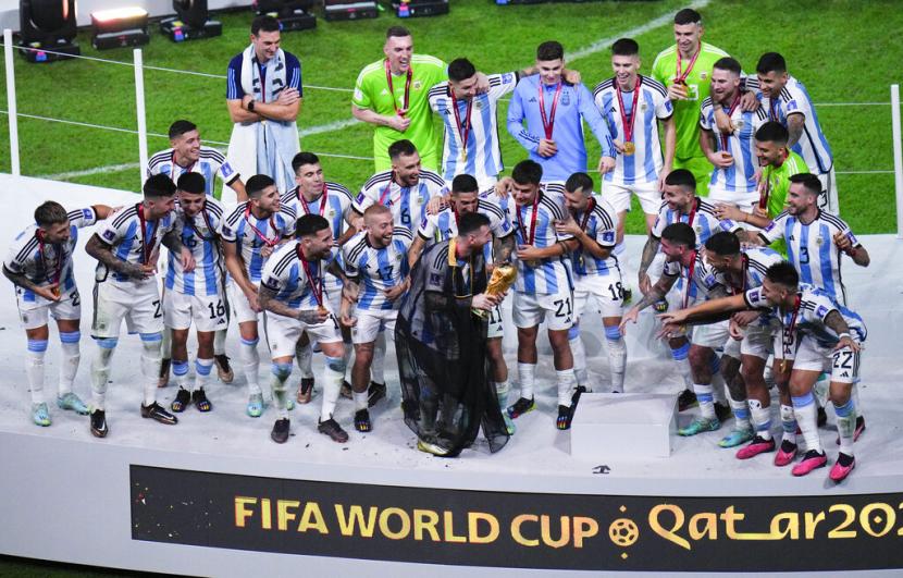  Pemain Argentina Lionel Messi memegang trofi saat ia merayakan bersama timnya pada akhir pertandingan sepak bola final Piala Dunia antara Argentina dan Prancis di Stadion Lusail di Lusail, Qatar,  Ahad (18/12/2022).