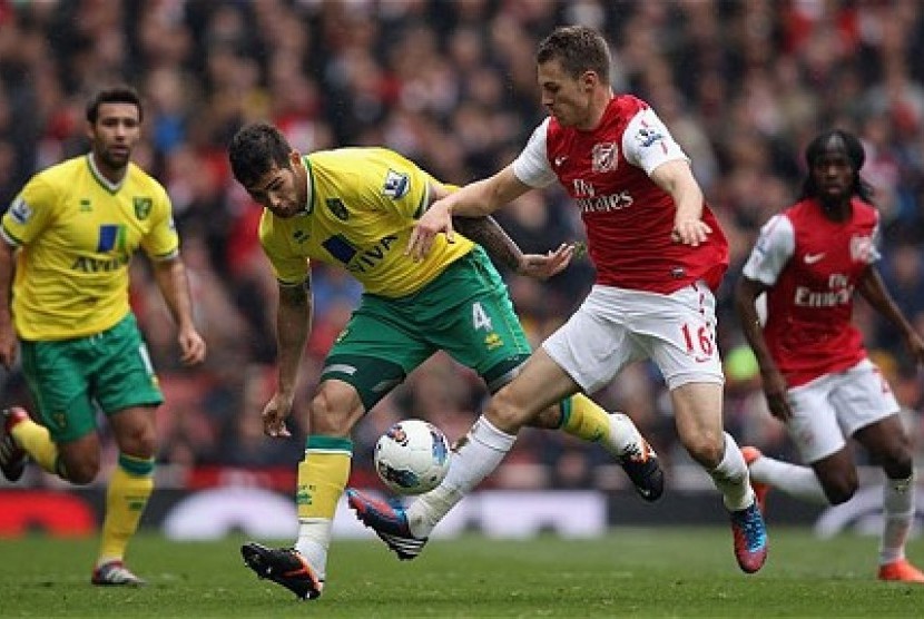 Pemain Arsenal, Aaron Ramsey (kanan), terlihat berebut bola dengan seorang pemain Norwich City. Pada laga Liga Primer yang berakhir Ahad (21/10) dini hari itu Arsenal takluk 1-0.