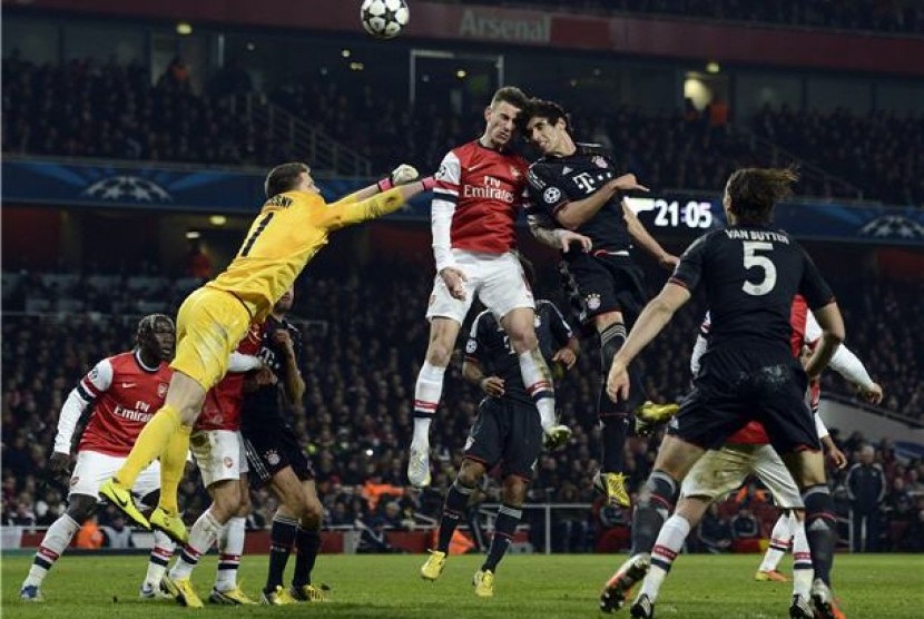 Pemain Arsenal, kiper Wojciech Szczesny (kiri) dan Laurent Koscielny (tengah), terlibat duel udara dengan pemain Bayern Muenchen, Javi Martinez, di leg pertama babak 16 besar Liga Champions.  