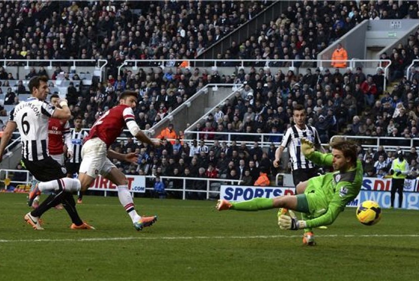 Pemain Arsenal, Olivier Giroud (tengah), melepaskan sundulan menjebol gawang Newcastle United dalam laga Liga Primer Inggris di St James Park, Newcastle, Ahad (29/12).