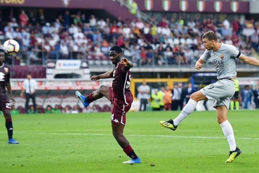Pemain AS Roma Edin Dzeko (kanan) melesakkan tendangan yang menghasilkan gol ke gawang Torino dalam pertandingan yang digelar di Turin Olympic Stadium, Italia, Ahad (19/8). Roma menang 1-0 di pertandingan ini 