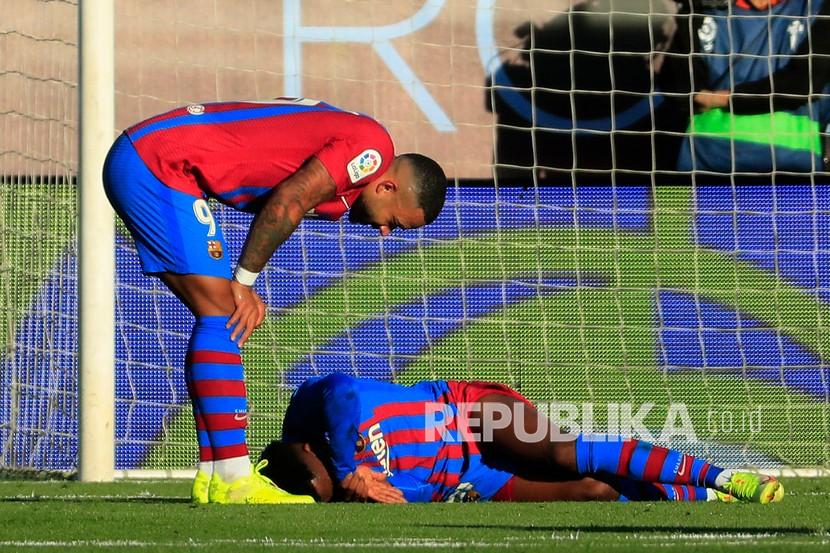 Pemain Barcelona Ansu Fati (kanan) terbaring terluka saat Memphis Depay bersandar padanya saat pertandingan sepak bola La Liga Spanyol antara Celta dan Barcelona di stadion Balaidos di Vigo, Spanyol,  Ahad (7/11) dini hari WIB. 