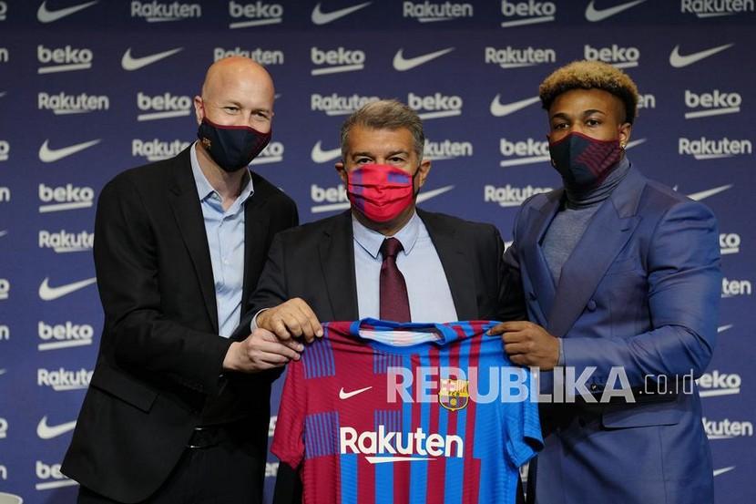  Pemain baru FC Barcelona Adama Traore (kanan) berpose dengan Presiden FC Barcelona, Joan Laporta (C), dan penasihat olahraga FC Barcelona, Jordi Cruyff, selama presentasinya di stadion Camp Nou di Barcelona, awal bulan ini. Barca belakangan memburu pemain-pemain tak berbajet mahal.