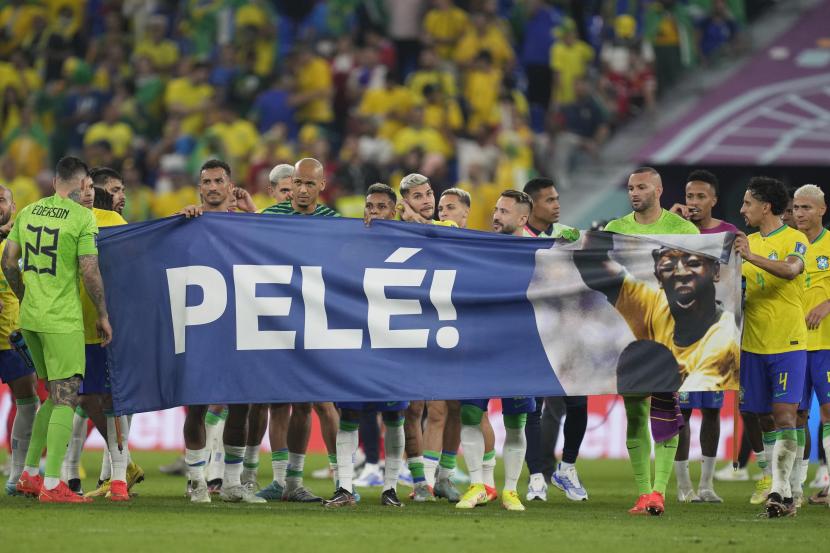 Pemain Brasil memegang spanduk untuk menghormati legenda sepak bola Brasil berusia 82 tahun Pele yang berada di sebuah rumah sakit di San Paulo pulih dari infeksi pernapasan pada akhir pertandingan sepak bola babak 16 besar Piala Dunia antara Brasil dan Korea Selatan di Stadium 974 di Doha, Qatar, Senin, 5 Desember 2022. 