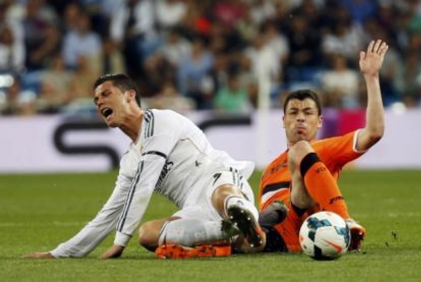 Pemain depan Real Madrid Cristiano Ronaldo (kiri) saat dijegal pemain Valencia Javier Fuego dalam lanjutan Laliga Spanyol di Stadion Santiago Bernabeu, Senin (5/5) dini hari.