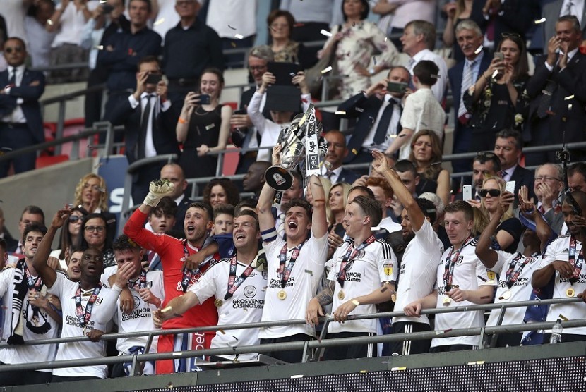 Pemain Fulham Tom Cairney (tengah) mengangkat trofi Championship, kasta kedua Liga Inggris, usai mengalahkan Aston Villa 1-0. Hasil ini membuat Fulham naik ke Liga Primer Inggris musim depan 