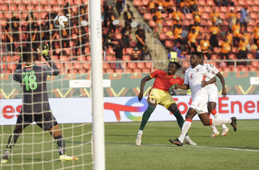 Pemain Guinea Mohamed Bayo, kiri, menembak ke gawang selama pertandingan babak 16 besar Piala Afrika 2022 antara Guinea dan Gambia di Stadion Kouekong, Bafoussam, Kamerun, Senin, 24 Januari 2022.
