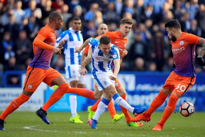 Pemain Huddersfield Town, Jack Payne (tengah) berusaha melepaskan tendangan dikawal para pemain Manchester City pada pertandingan Piala FA di John Smith's Stadium, Huddersfield, Sabtu (18/2). 