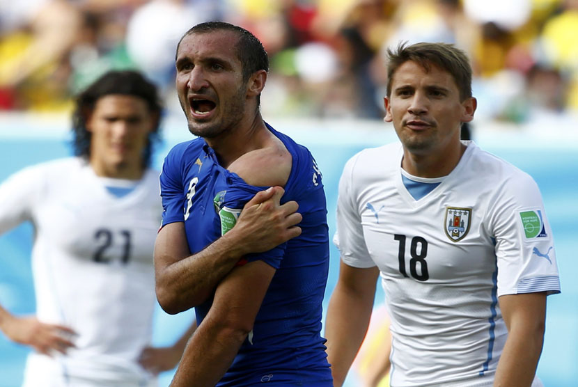 Pemain Italia, Giorgio Chiellini, memperlihatkan bahunya yang diklaim digigit striker Uruguay, Luis Suarez, selama pertandingan terakhir Grup D Piala Dunia 2014 Brasil di Arena Dunas, Natal, Selasa (24/6). 