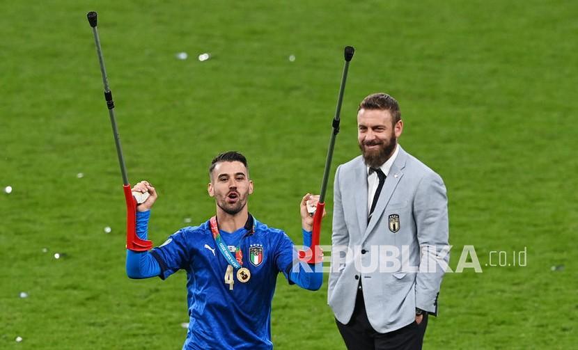 Pemain Italia Leonardo Spinazzola yang cedera pada awal turnamen melakukan selebrasi setelah Italia memenangkan final UEFA EURO 2020 antara Italia dan Inggris di London, Inggris, Senin (12/7) dini hari WIB.. Di sebelah kanan adalah Angelo de Rossi, anggota staf pelatih Italia. 