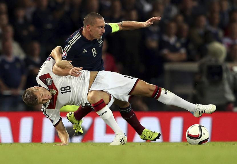 Pemain Jerman Toni Kroos, di posisi bawah, berebut bola dengan kapten Skotlandia Scott Brown selama pertandingan kualifikasi Grup D Euro 2016. Jerman dan Skotlandia akan bertemu kembali, kali ini di laga pertama Grup A Euro 2024 di Munchen, Jerman, Sabtu (15/6/2024) dini hari WIB.  