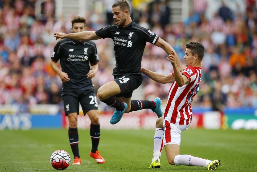 Pemain Liverpool Jordan Henderson beraksi dihadapan pemain Stoke, Marco van Ginkel, dalam laga Stoke City kontra Liverpool, Ahad (9/8)