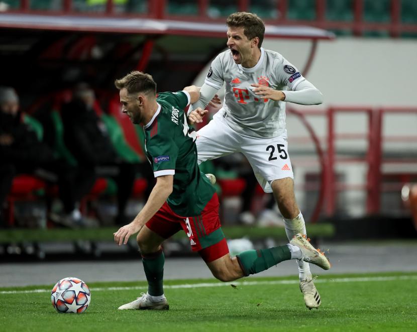 Pemain Lokomotiv Moskow Maciej Rybus (kiri) berebut dengan gelandang Bayern Muenchen Thomas Mueller pada laga kedua Grup A Liga Champions 2020/2021, Rabu (28/10) dini hari WIB.