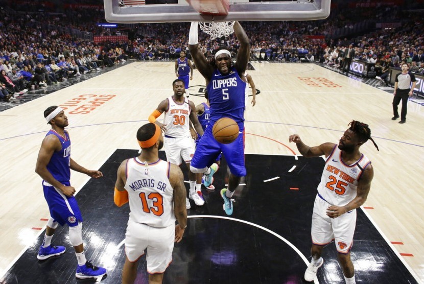 Pemain Los Angeles Clippers Montrezl Harrel (tengah) melakukan dunk di tengah penjagaan para pemain New York Knicks.