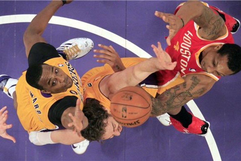 Pemain Los Angeles Lakers, Dwight Howard (kiri) dan Pau Gasol (tengah), berebut rebound dengan pemain Houston Rockets, Greg Smith, dalam laga NBA di Los Angeles pada Rabu (17/4). 