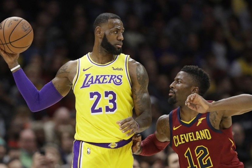 Pemain Los Angeles Lakers, LeBron James (kiri) mencoba mengarahkan bola dengan adangan pemain Cleveland Cavaliers David Nwaba dalam pertandingan lanjutan NBA, Kamis (22/11) di Cleveland. 