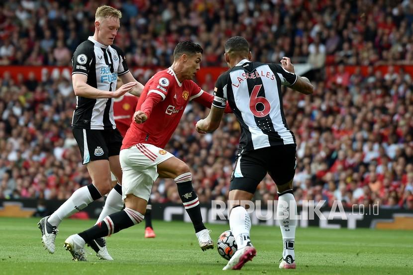  Pemain Manchester United Cristiano Ronaldo menggiring bola antara pemain Newcastle Sean Longstaff dan Jamaal Lascelles, kanan, pada pertandingan sepak bola Liga Inggris antara Manchester United dan Newcastle United di stadion Old Trafford di Manchester, Inggris,  Sabtu (11/9).