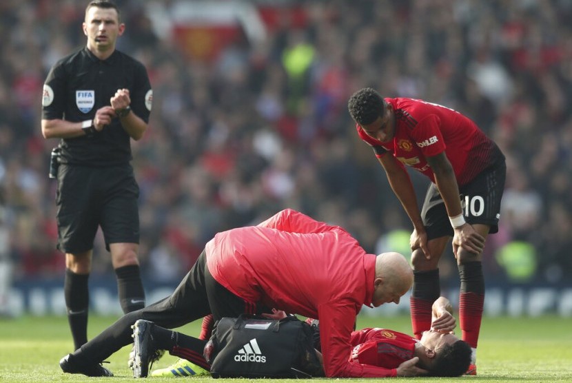 Pemain Manchester United Jesse Lingard terbaring di lapangan akibat cedera.