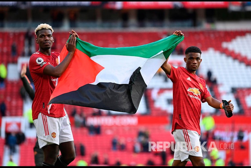 Pemain Manchester United Paul Pogba (kiri) dan Amad (kanan) membentangkan bendera Palestina setelah pertandingan sepak bola Liga Primer Inggris antara Manchester United dan Fulham FC di Manchester, Inggris, Rabu (19/5) dini hari WIB. 