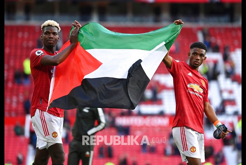 Orang-orang di Barat saja peduli terhadap nasib Palestina. Tampak pemain Manchester United Paul Pogba (kiri) dan Amad (kanan) mengibarkan bendera Palestina ketika menyapa suporter setelah pertandingan sepak bola Liga Primer Inggris antara Manchester United dan Fulham FC di Manchester, Inggris, 18 Mei 2021. 