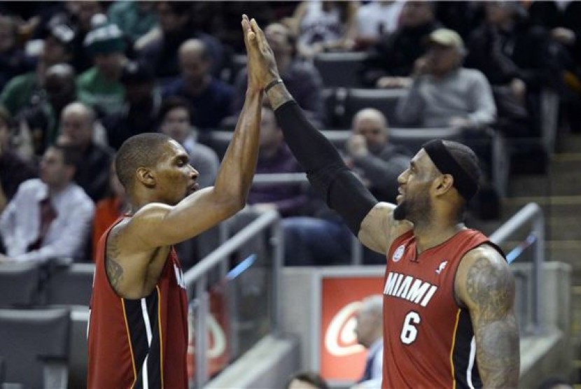 Pemain Miami Heat, LeBron James (kanan) dan Chris Bosh, melakukan high five saat menghadapi Toronto Raptors di laga NBA di Toronto pada Ahad (17/3). 