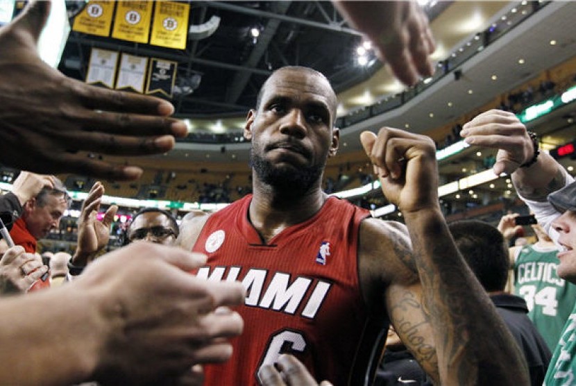 Pemain Miami Heat, LeBron James, melakukan selebrasi bersama fans usai menaklukkan Boston Celtics di laga NBA di Boston pada Senin (18/3). 