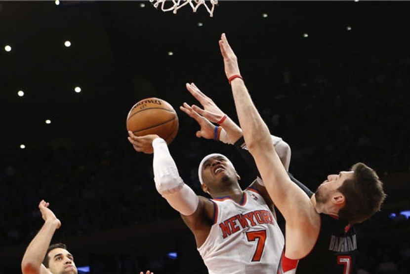 Pemain New York Knicks, Carmelo Anthony (tengah), melakukan drives menembus pertahanan pemain Toronto Raptor, Andrea Bargnani (kanan), di pertandingan NBA di New York pada Rabu (13/2).  