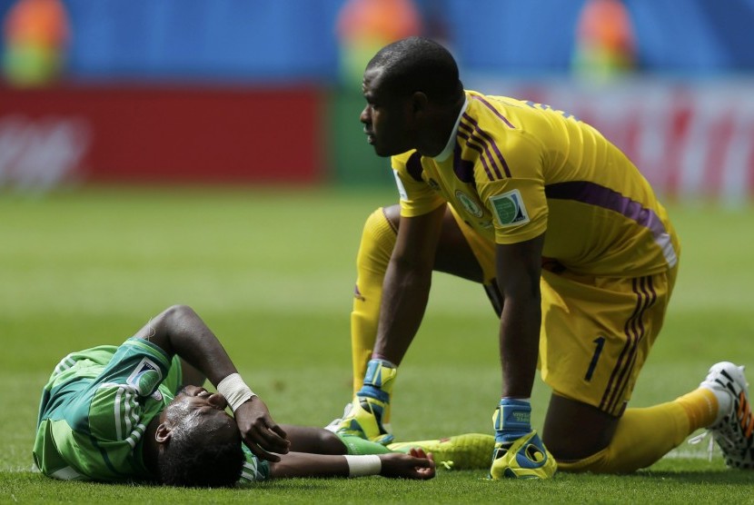 Pemain Nigeria, Vincent Enyeama (kanan), memeriksa   rekannya, Ogenyi Onazi, yang tergeletak setelah beradu   fisik dengan pemain Prancis di laga babak 16 besar Piala   Dunia 2014 di Stadion Nasional, Brasilia, Senin (30/6).   