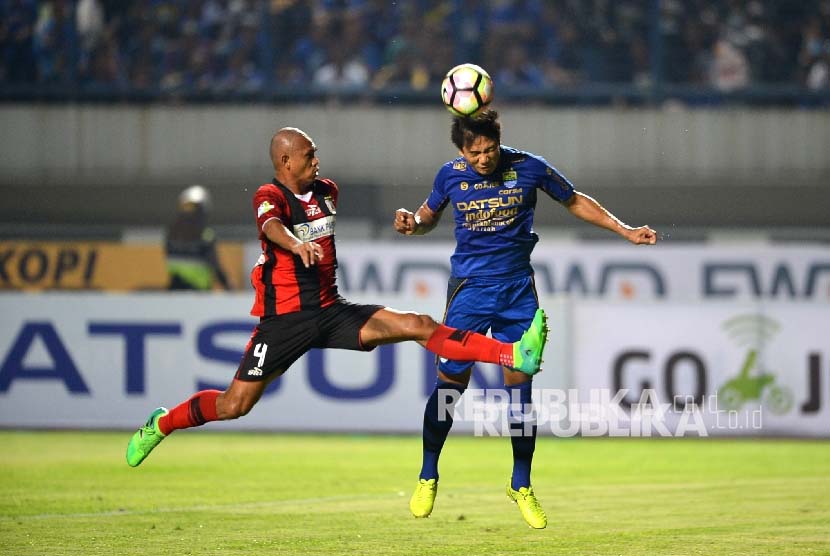 Pemain Persib Bandung Dedi Kusnandar (biru) menyundul bola dibayangi pemain Persipura Ricardo Salampessy.
