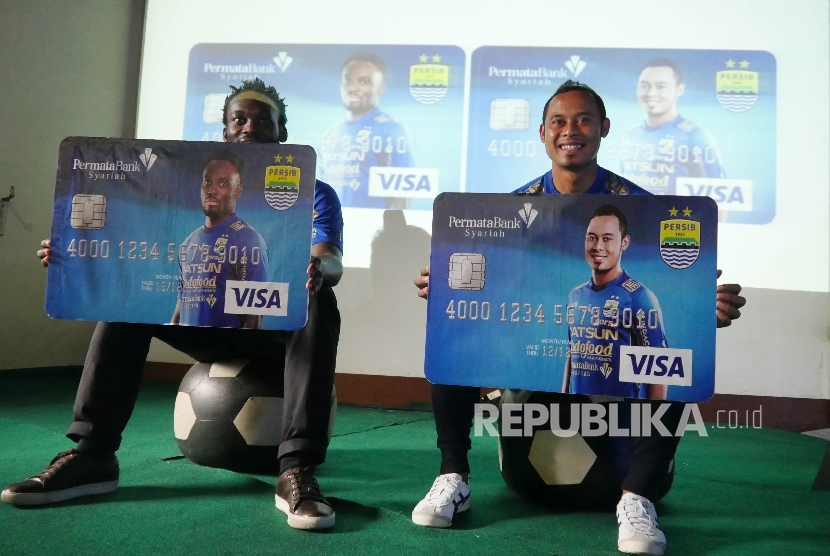 Pemain Persib Essien (kiri) dan Atep (kanan) memegang mock up kartu Permata Syariah Persib DebitPlus, di Graha Persib, Jalan Tamansari, Kota Bandung, Kamis (7/8).
