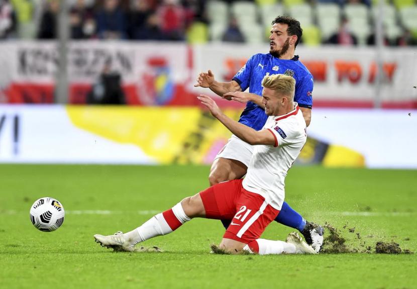 Pemain Polandia Kamil Jozwiak (putih) merebut bola dari penggawa timnas Italia Alessandro Florenzi dalam pertandingan UEFA Nations League, Senin (12/10) dini hari WIB. Polandia menahan imbang Italia 0-0. 