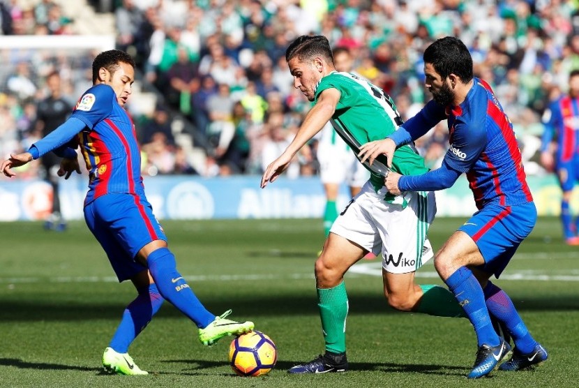 Pemain Real Betis Alex Alegria (tengah) berusaha melewati dua pemain Barcelona. 