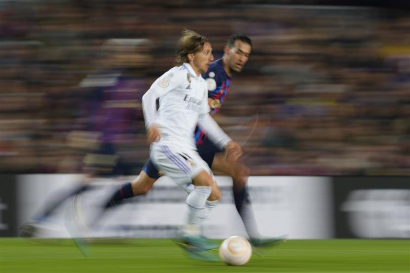 Pemain Real Madrid Luka Modric berlari dikejar oleh kapten Barcelona Sergio Busquets pada leg kedua semifinal Copa Dep Rey, Kamis (6/4/2023). 