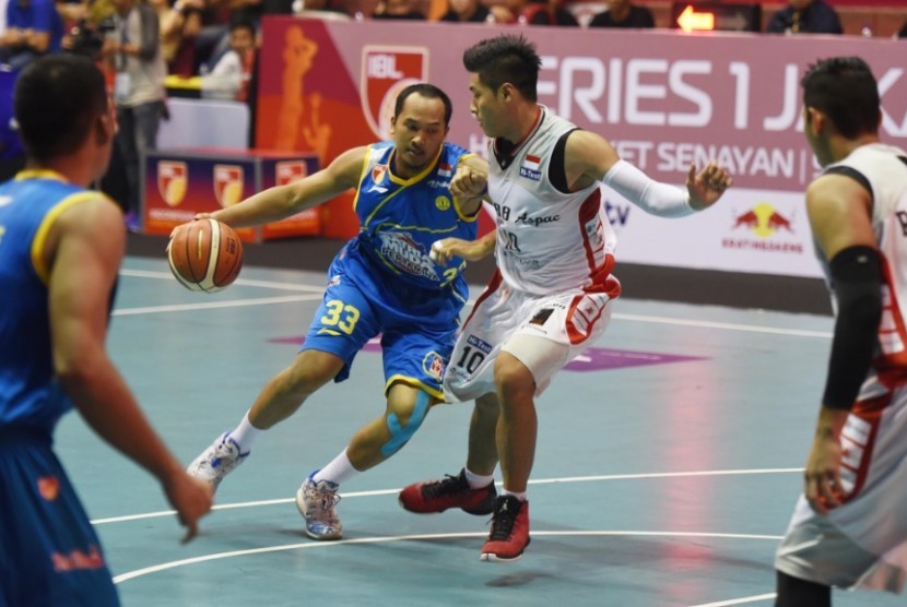 Pemain Satria Muda Pertamina Arki Dikania Wisnu membawa bola berusaha melewati pemain Aspac dalam pertandingan IBL.