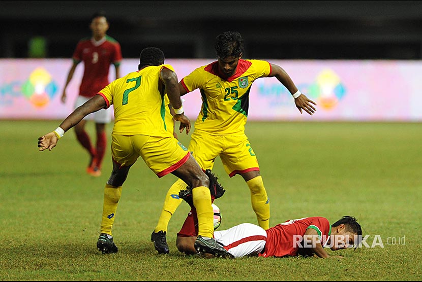 Pemain sayap Indonesia Febri Hariyadi dijatuhkan dua pemain Guyana dalam pertandingan persahabatan Indonesia melawan Guyana di Stadion Patriot Chandrabhaga,  Bekasi, Jawa Barat, Sabtu (25/11). 