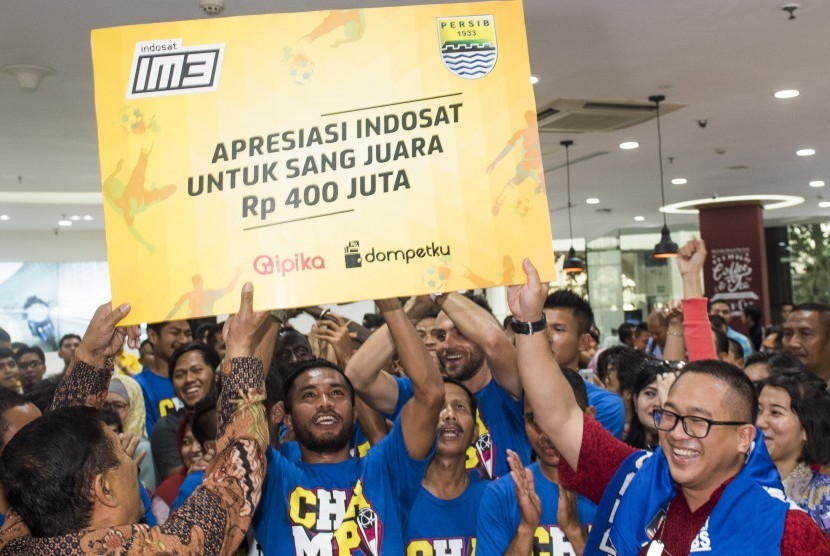 Pemain sepak bola Persib Bandung mengangkat hadiah simbolis disaksikan President Director dan CEO Indosat Alexander Rusli (kanan) dan Manager Persib Bandung Umuh Muchtar (kiri) saat perayaan kemenangan di kantor Indosat, Jakarta, Senin (19/10).