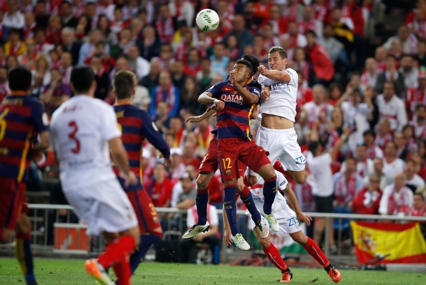  Pemain Sevilla, Kevin Gameiro (kanan) melompat ke udara untuk berebut bola dengan pemain Barcelona, Rafinha dalam babak final Copa del Rey di Vicente Calderon Stadium, Madrid, Ahad (22/5) waktu setempat. 