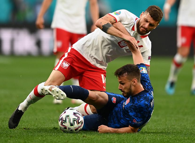 Pemain Slovakia Jakub Hromada (bawah) berduel dengan penggawa Polandia Mateusz Klich ketika kedua tim bertanding pada laga Grup E Piala Dunia 2020, Senin (14/6).