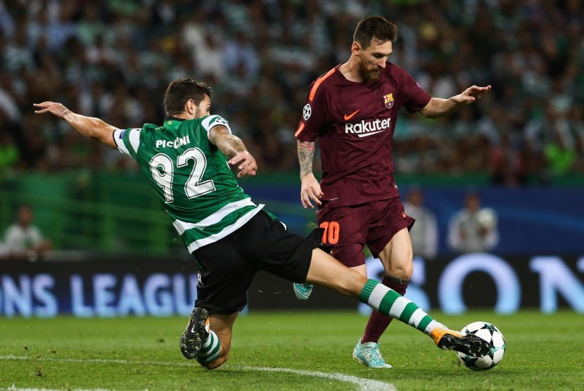 Pemain Sporting Cristiano Piccini (kiri) berusaha merebut bola dari kaki pemain Barcelona Lionel Messi ketika kedua tim bertemu pada Liga Champions Grup D di Stadion Jose Alvalade, Lisbon, Portugal, Kamis (28/9) dini hari WIB.