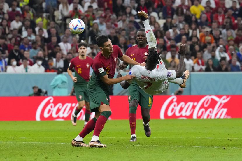 Pemain Swiss Breel Embolo berusaha menyambungkan tembakan melawan pemain Portugal Diogo Dalot pada pertandingan sepak bola babak 16 besar Piala Dunia antara Portugal dan Swiss, di Stadion Lusail di Lusail, Qatar, Selasa, 6 Desember 2022. 