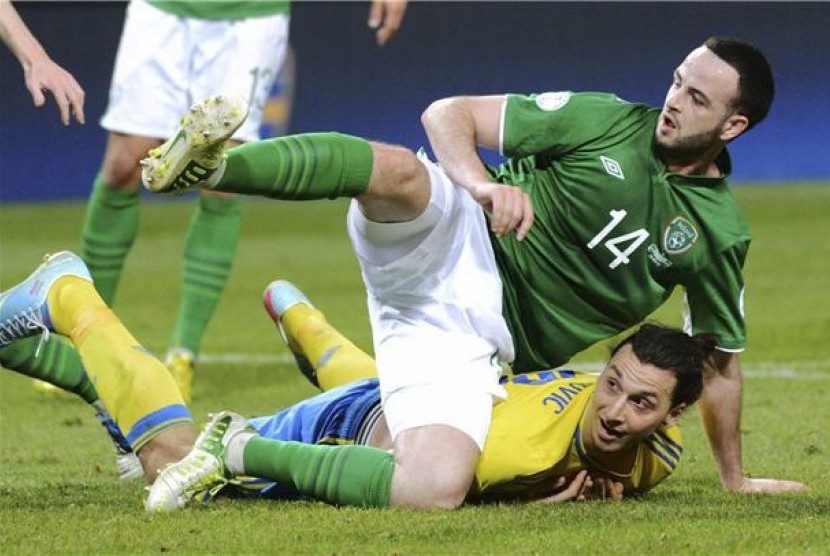 Pemain timnas Irlandia, Marc Wilson (kiri), terjatuh saat adu fisik dengan striker timnas Swedia, Zlatan Ibrahimovic, di laga kualifikasi Piala Dunia 2014 di Stockholm pada Jumat (22/3). 