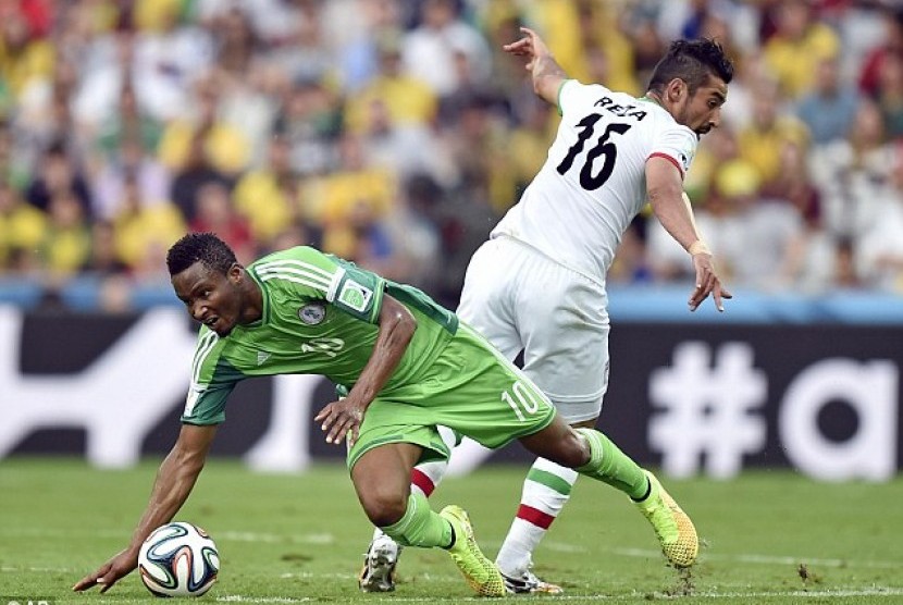  Pemain timnas Nigeria, John Obi Mikel berebut bola dengan pemain timnas Iran, Reza Ghoochannejhad.