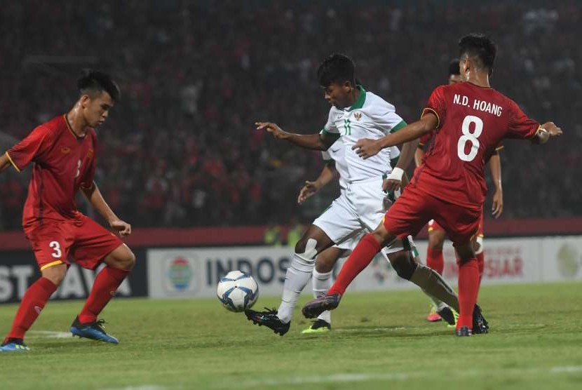 Pemain Timnas U-16 Indonesia, Mochammad Supriadi (tengah), berusaha melewati pesepak bola Vietnam U-16, Ngo Duc Hoang (kanan) dan Vo Quoc Dan dalam laga penyisihan Grup A Piala AFF U-16 di Gelora Delta Sidoarjo, Sidoarjo, Jawa Timur, Kamis (2/8). 