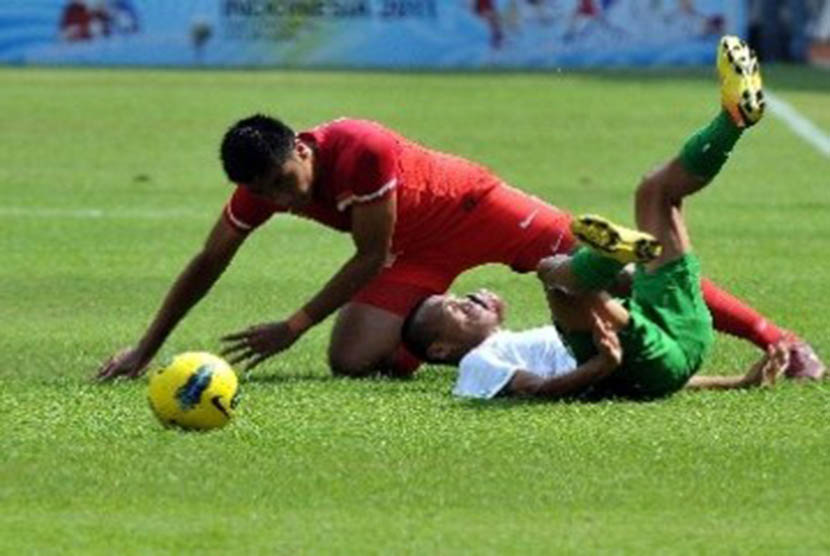 Pemain Timnas U23 Indonesia, Ferdinand Sinaga (kanan), terjatuh setelah dilanggar pemain Singapura di laga Grup A cabang sepak bola SEA Games 2011.