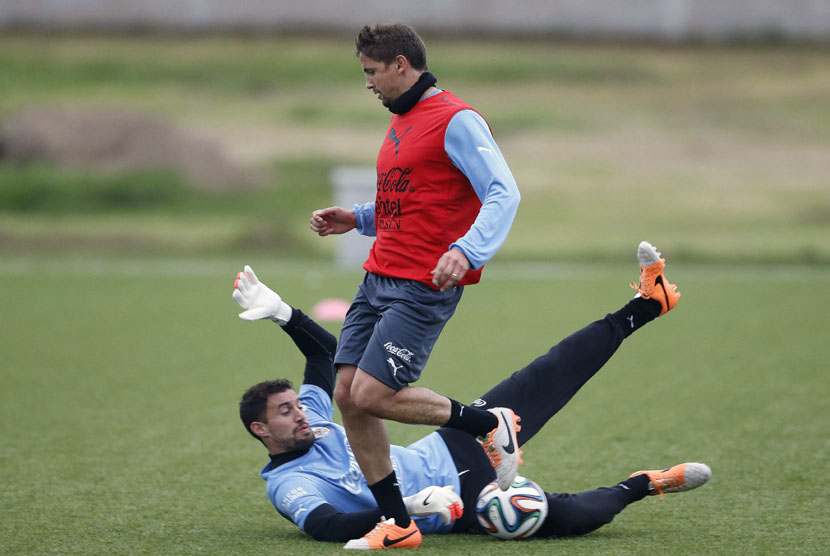 Pemain Timnas Uruguay, Martin Silva (di tanah) dan Gaston Ramirez, dalam sesi latihan di Motevideo pada 21 Mei. 