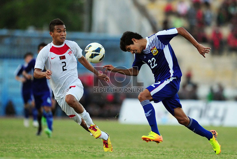   Pemain Timor Leste Nidio Octavio Das Dores Neto (putih) berebut bola dengan pemain Laos Sisawad Dalavong di Stadion Delta Sidoarjo, Jawa Timur, Ahad (22/9). (Republika/Edwin Dwi Putranto)