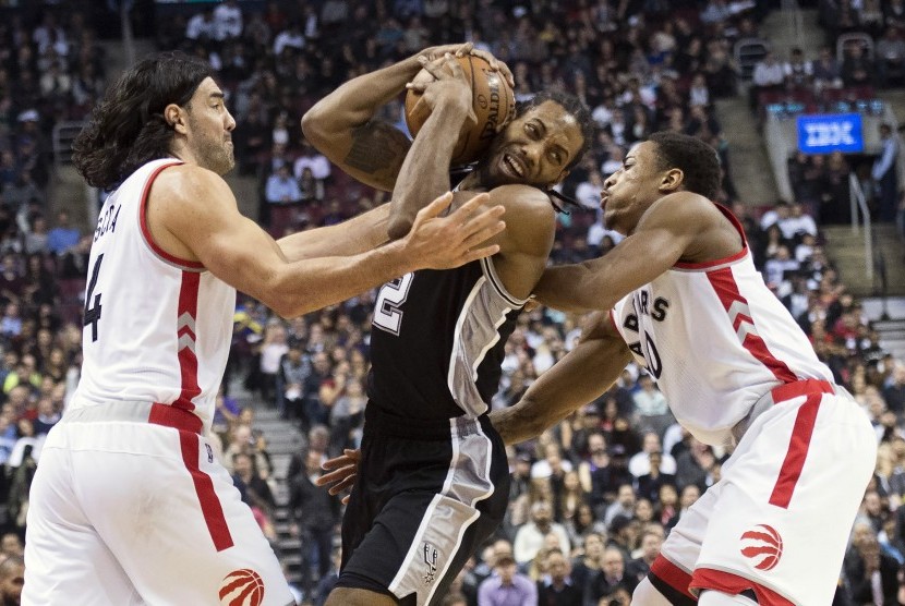 Pemain Toronto Raptors, Demar Derozan (kanan), berupaya menghalangi pemain San Antonio Spurs, Kawhi Leonard (tengah), dalam pertandingan NBA di Toronto pada Rabu (9/12).  