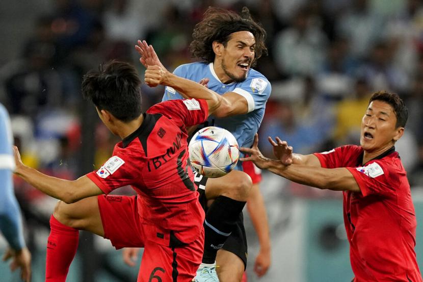 Pemain Uruguay Edinson Cavani (tengah) berebut bola dengan pemain Korea Selatan Hwang In-beom, kiri, dan Jung Woo-young selama pertandingan sepak bola grup H Piala Dunia antara Uruguay dan Korea Selatan, di Stadion Kota Pendidikan di Al Rayyan, Qatar, Kamis (24/11/2022).. 